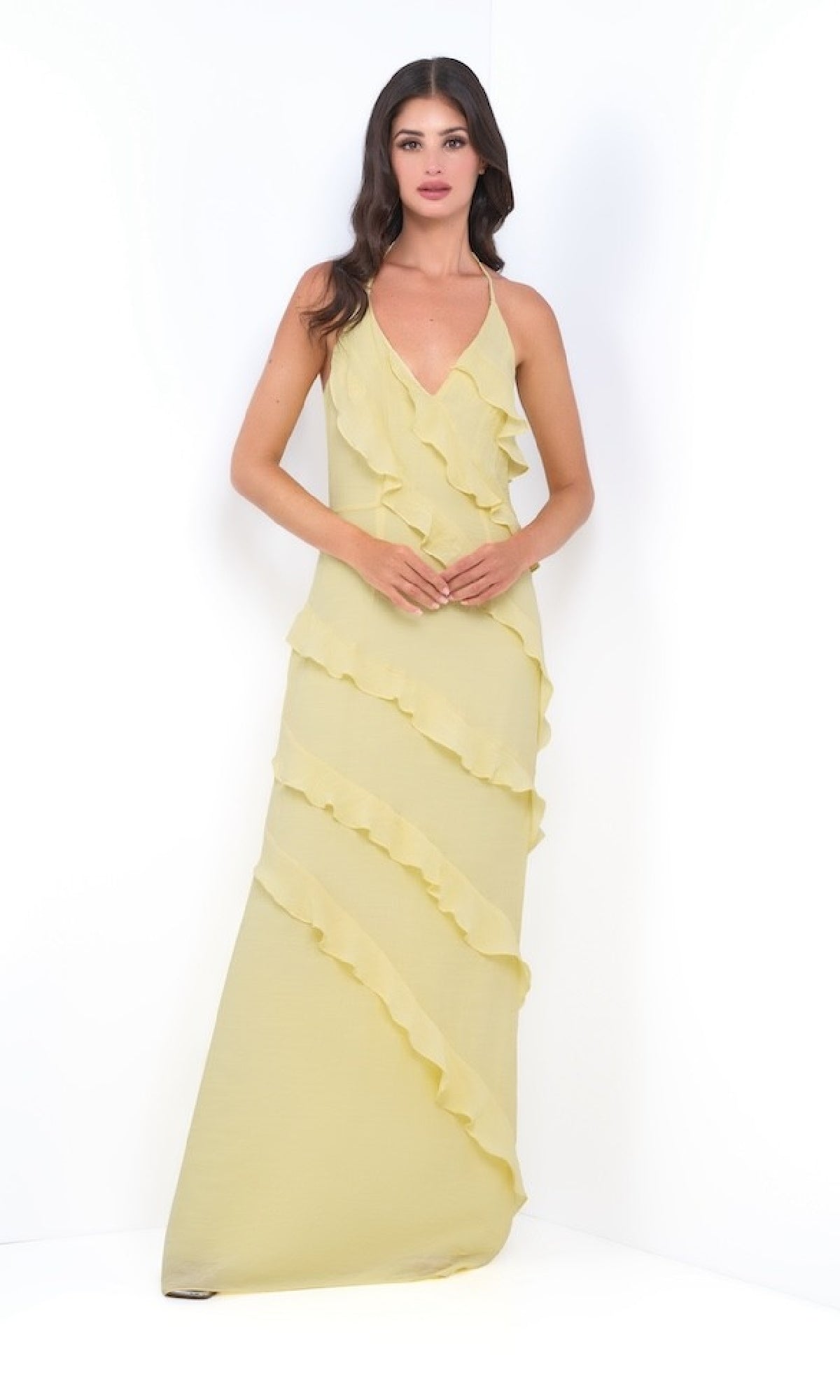 Woman wearing the Remi by Velvi V-Neck Halter Ruffled Long Prom Dress in light yellow, featuring diagonal ruffle layers, standing against a plain white background.